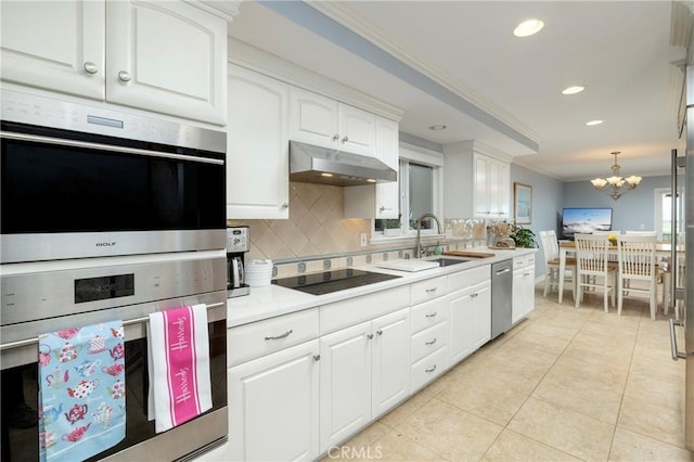 kitchen with under cabinet range hood, tasteful backsplash, appliances with stainless steel finishes, white cabinets, and light countertops