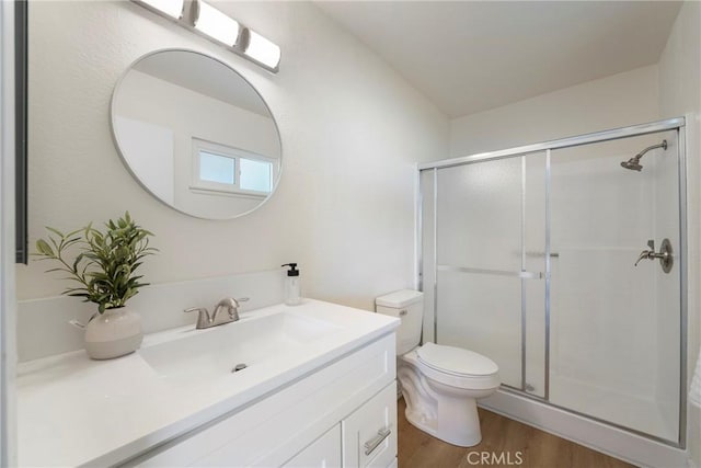 full bathroom featuring vanity, toilet, wood finished floors, and a shower stall