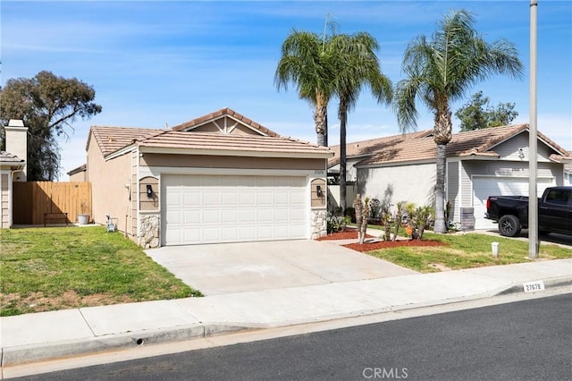 single story home with a front yard, fence, driveway, an attached garage, and a tiled roof