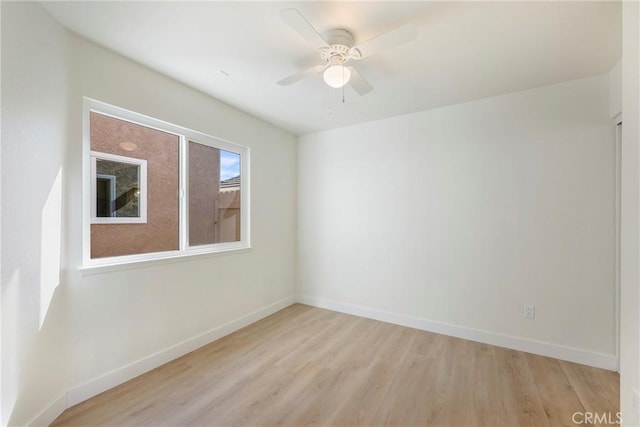 spare room with baseboards, light wood-type flooring, and ceiling fan