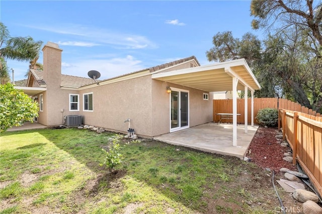 rear view of property with fence, central air condition unit, stucco siding, a yard, and a patio