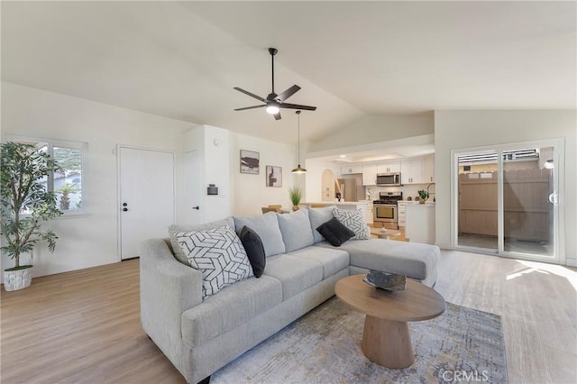 living area featuring light wood finished floors, ceiling fan, and vaulted ceiling