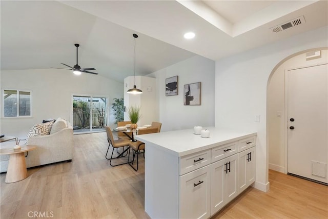 kitchen featuring light wood finished floors, visible vents, open floor plan, arched walkways, and white cabinets