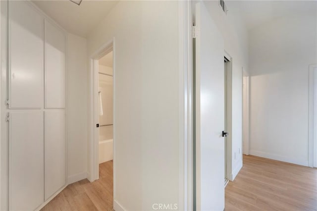 hallway featuring visible vents, baseboards, and light wood-style floors