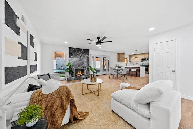 living area featuring a high end fireplace, visible vents, ceiling fan, light wood-type flooring, and recessed lighting