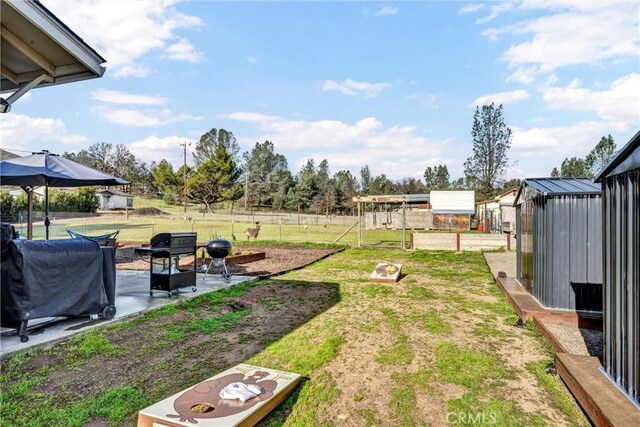 view of yard featuring an outdoor structure, fence, and a patio