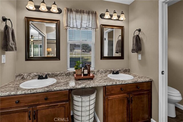 bathroom with double vanity, toilet, and a sink