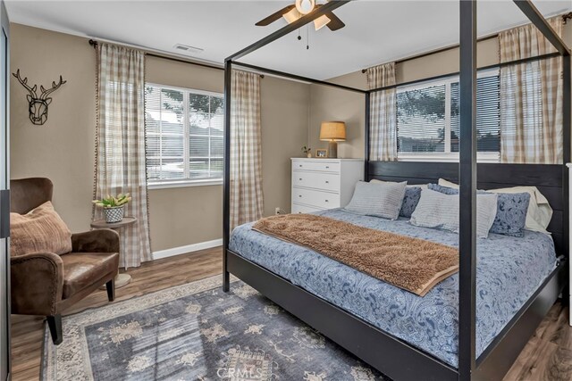 bedroom featuring ceiling fan, visible vents, baseboards, and wood finished floors