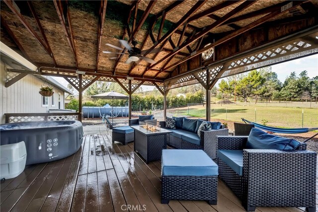 deck featuring a lawn, an outdoor living space with a fire pit, and fence