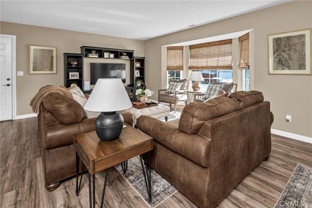 living area featuring visible vents, baseboards, and wood finished floors