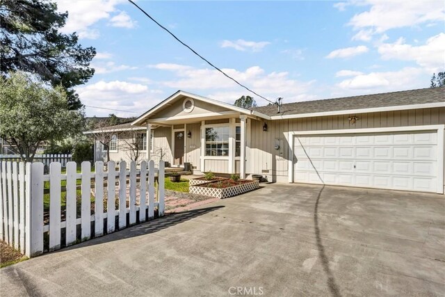 ranch-style home featuring a fenced front yard, driveway, an attached garage, and roof with shingles