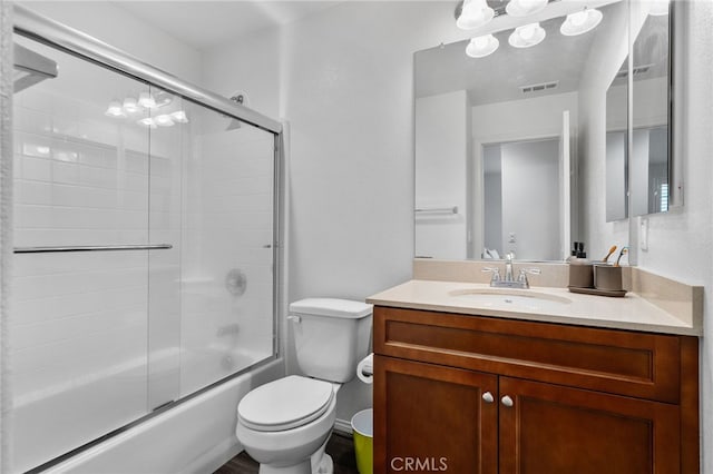 bathroom with visible vents, combined bath / shower with glass door, toilet, and vanity