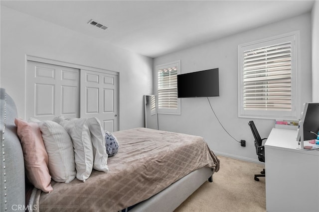 carpeted bedroom with visible vents, baseboards, and a closet