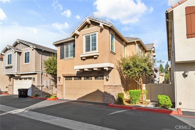 view of front of home featuring stucco siding, a tile roof, a garage, and fence