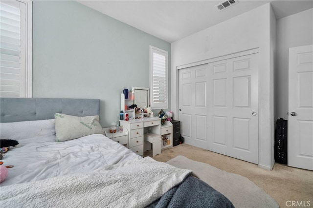 bedroom with visible vents, light carpet, and a closet