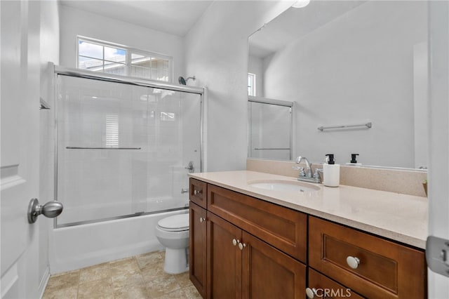 full bathroom featuring toilet, vanity, and shower / bath combination with glass door