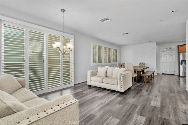 living room featuring visible vents, a notable chandelier, and wood finished floors