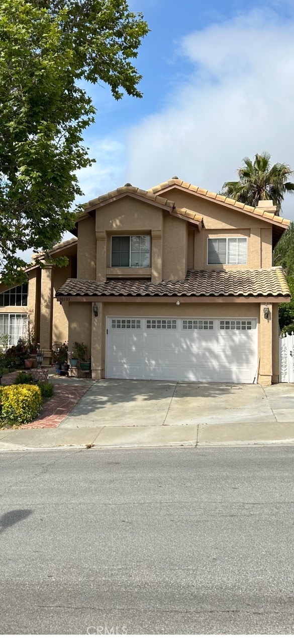 view of front of home with stucco siding, a tiled roof, concrete driveway, and a garage