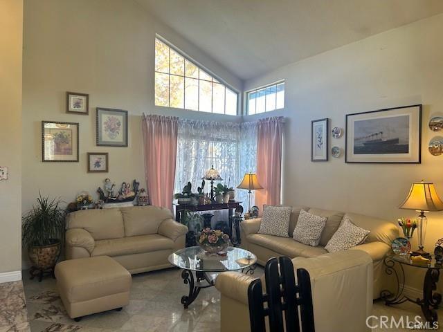 living room with baseboards and high vaulted ceiling