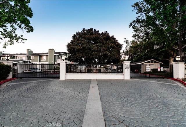 view of road with a gated entry, curbs, and a gate