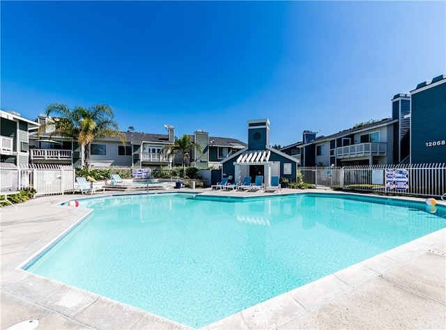 community pool with a patio area, a residential view, and fence