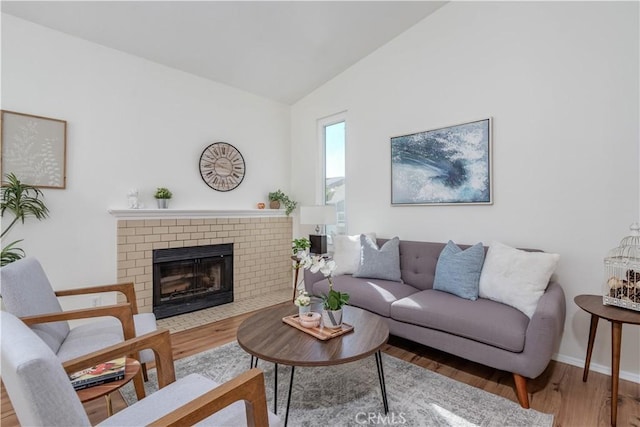 living room with baseboards, wood finished floors, a fireplace, and vaulted ceiling