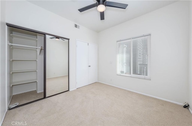 unfurnished bedroom with carpet, baseboards, visible vents, ceiling fan, and multiple closets