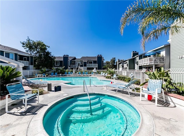 pool featuring a residential view, a patio, a hot tub, and fence