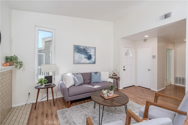 living room with baseboards, visible vents, and light wood finished floors