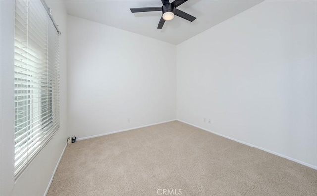 empty room featuring a ceiling fan, baseboards, and light carpet