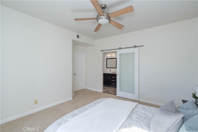 bedroom featuring light carpet, visible vents, baseboards, and a barn door