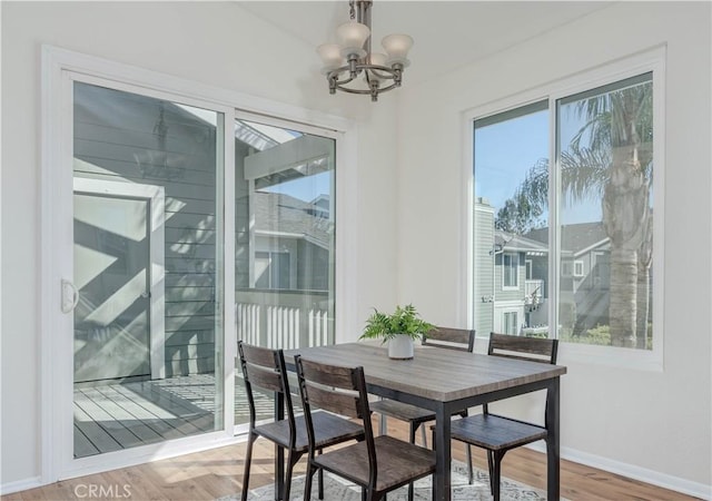 dining room featuring baseboards, light wood-style floors, and an inviting chandelier