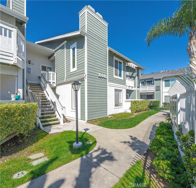 view of home's community with stairs and a lawn