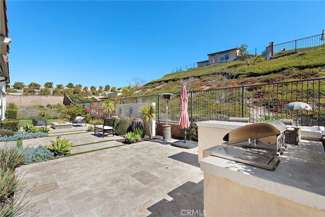 view of patio featuring exterior kitchen, a fire pit, fence, and grilling area