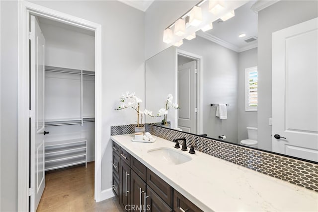 bathroom with vanity, visible vents, ornamental molding, a spacious closet, and toilet