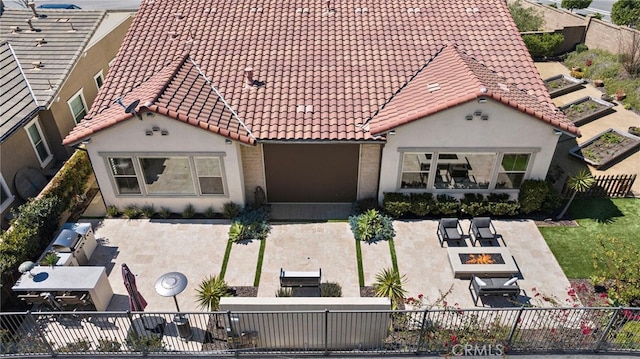 view of front of house featuring a tile roof, fence private yard, an outdoor fire pit, and a patio