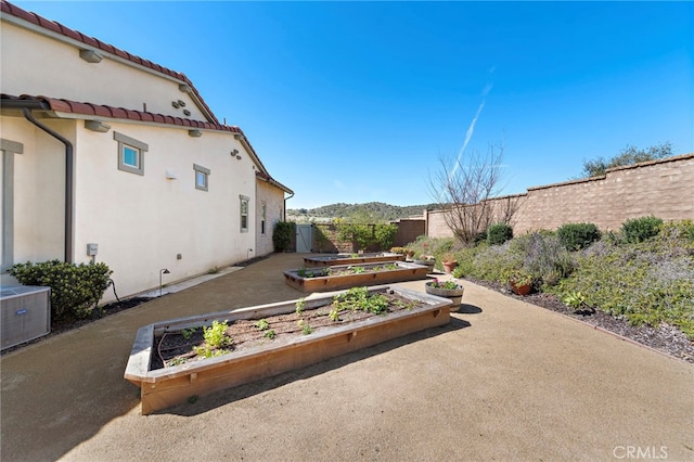 view of yard with cooling unit, fence, and a garden