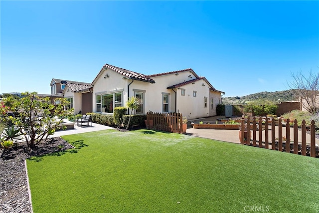 rear view of property with stucco siding, fence, a yard, and a patio area