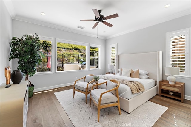 bedroom featuring hardwood / wood-style floors, crown molding, multiple windows, and baseboards