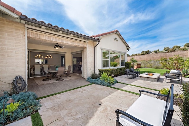 view of patio featuring outdoor dining area, fence, ceiling fan, and an outdoor fire pit