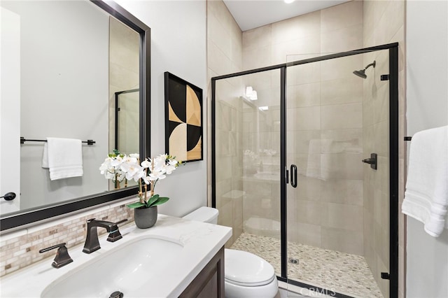 full bath featuring vanity, decorative backsplash, toilet, and a stall shower