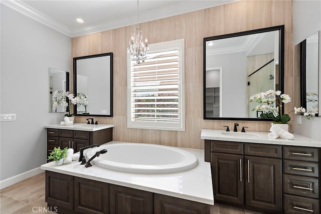 bathroom with a garden tub, two vanities, a sink, crown molding, and a chandelier