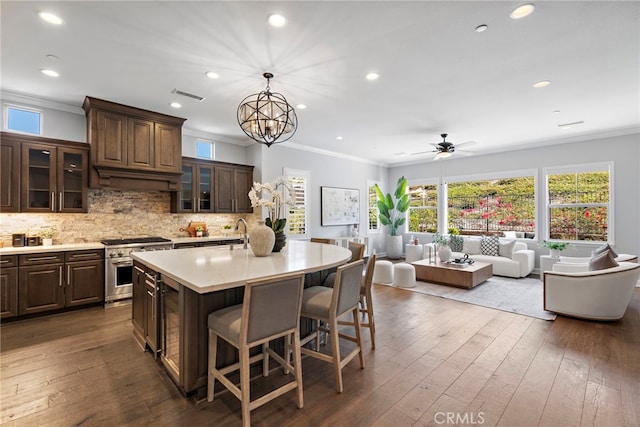 kitchen featuring visible vents, backsplash, light countertops, dark wood-style floors, and high end range