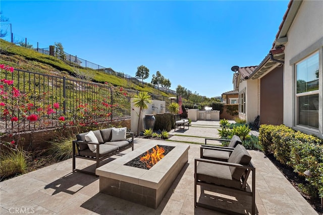 view of patio featuring an outdoor kitchen, an outdoor living space with a fire pit, and a fenced backyard