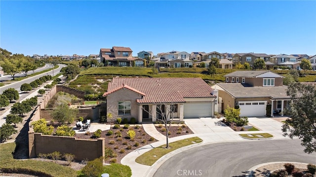 view of front of property with a residential view, a tiled roof, concrete driveway, and a garage