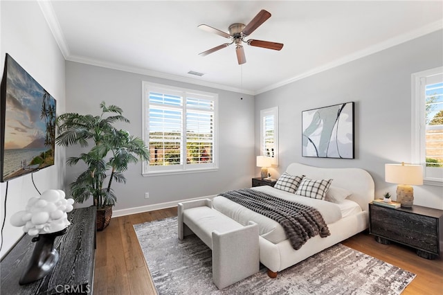 bedroom with baseboards, wood finished floors, visible vents, and ornamental molding