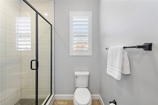 full bathroom featuring a shower stall, toilet, and baseboards