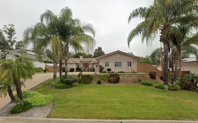 exterior space featuring fence, a front yard, stucco siding, a chimney, and decorative driveway