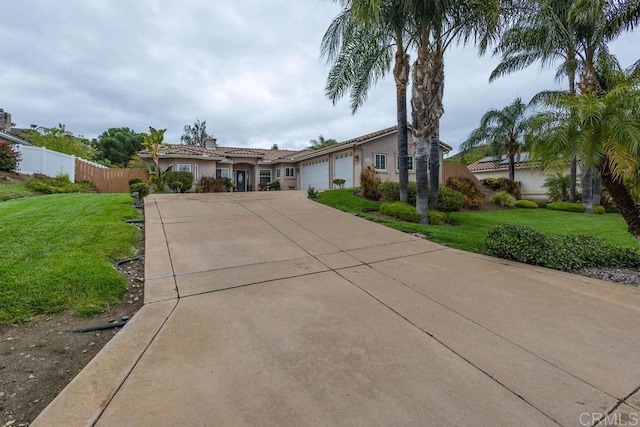 view of front of property with fence, concrete driveway, a front yard, stucco siding, and an attached garage