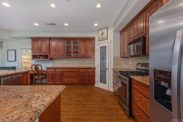 kitchen with light stone counters, visible vents, stainless steel appliances, and dark wood-type flooring